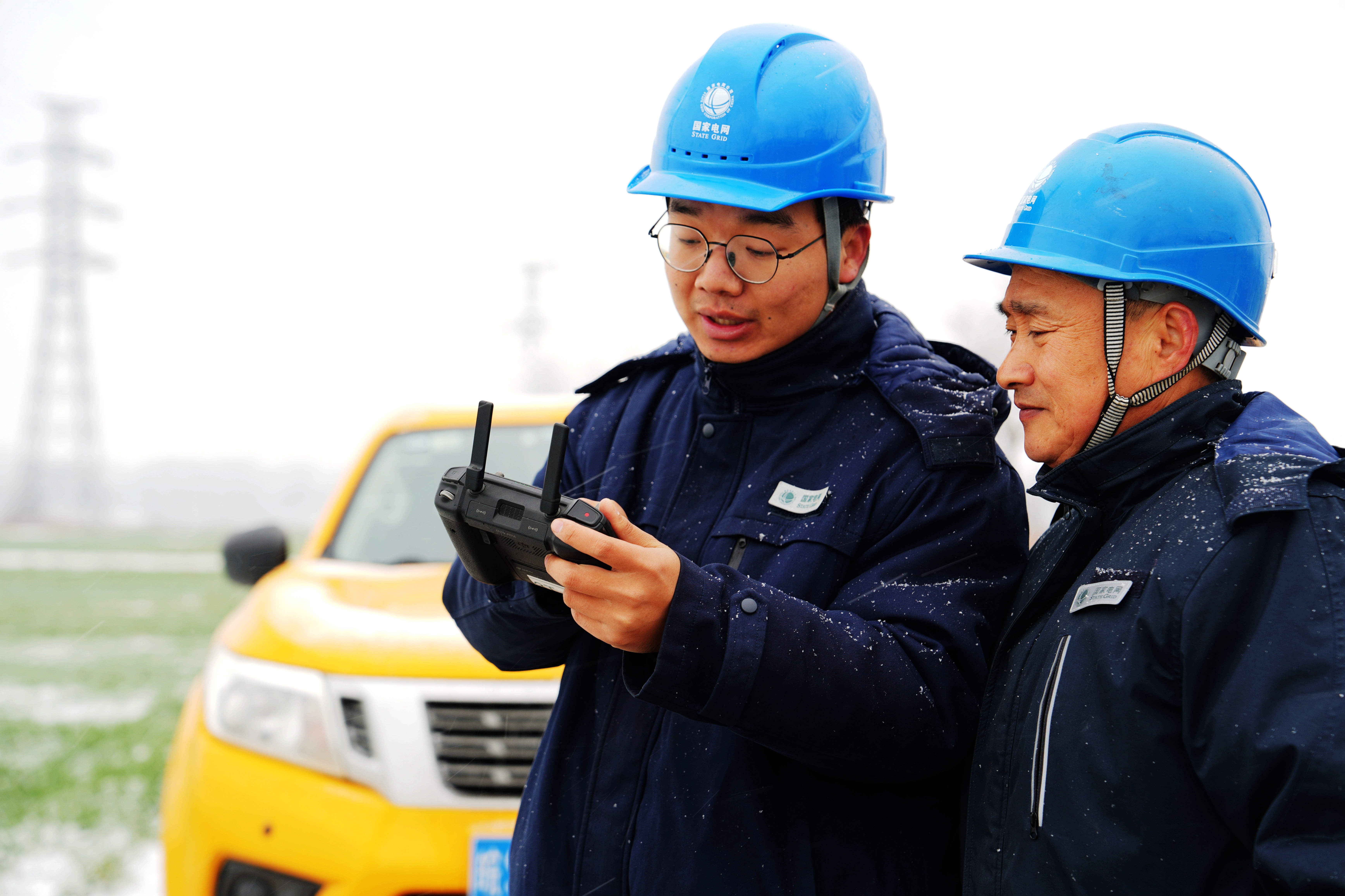 图为1月19日上午，在利辛县城北镇，国网利辛县供电公司人员正在使用无人机对110千伏夏铁727线的杆塔绝缘子覆冰情况进行观察。（刘喆）