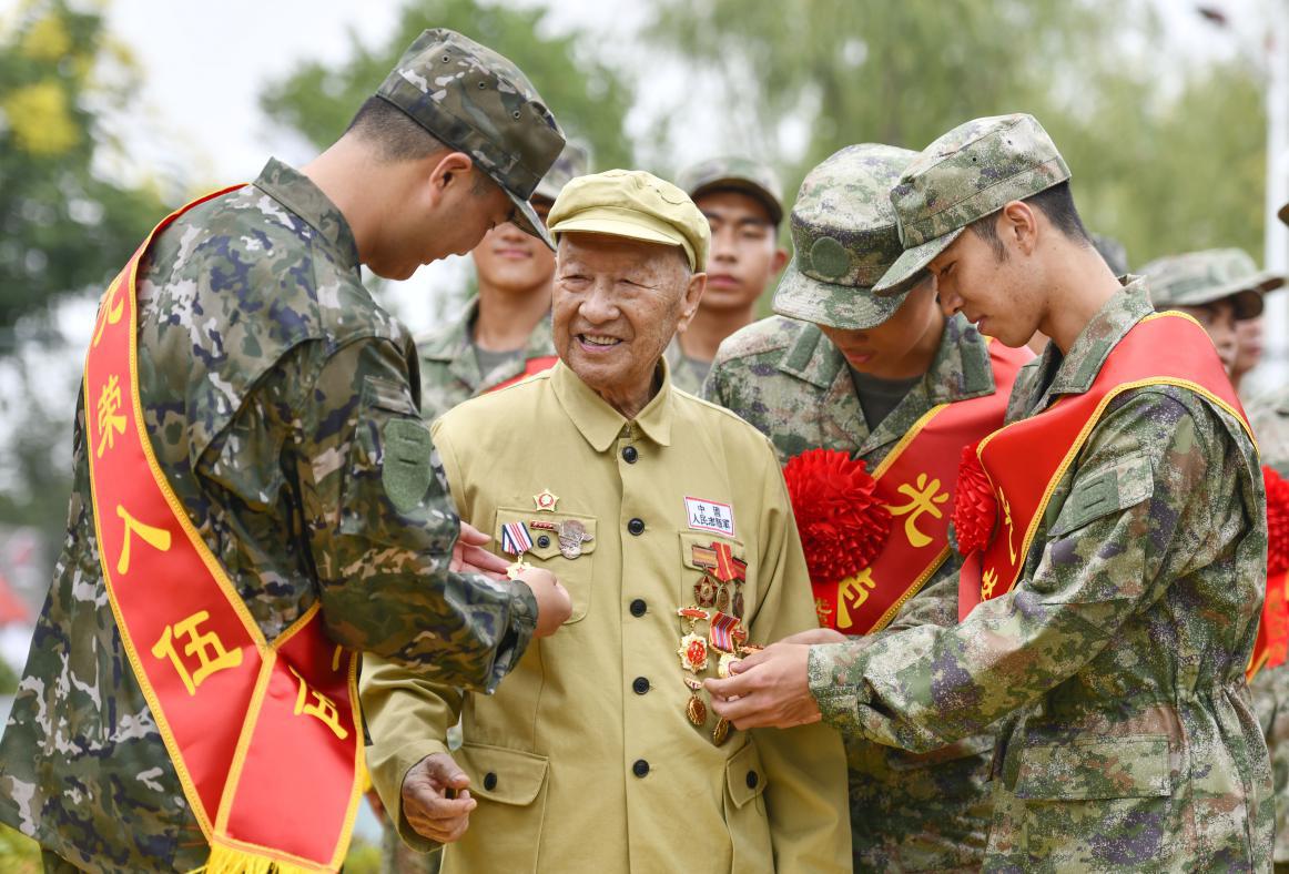 图9：2024年9月14日，安徽合肥，今年91岁抗美援朝老兵郑尊礼与即将奔赴军营的新兵分享军功章的故事。