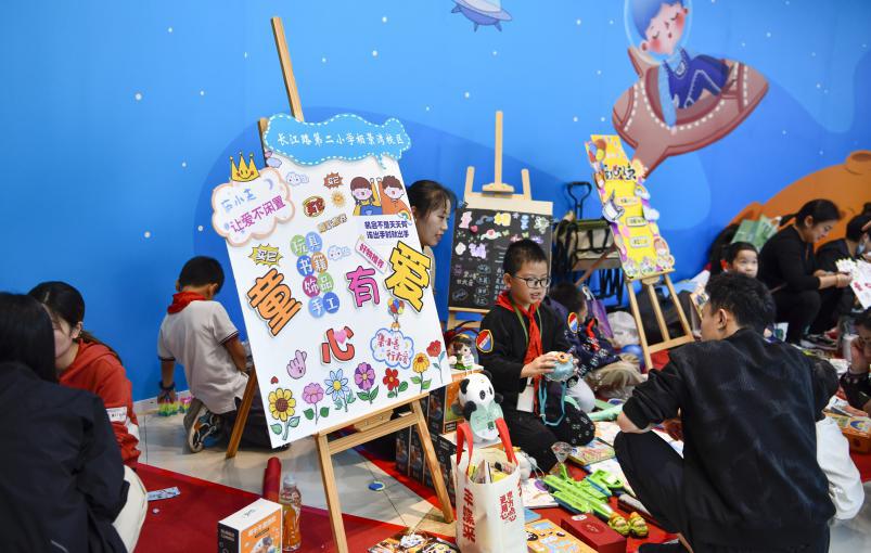 图4：2024年10月19日，安徽合肥，在安徽省合肥市庐阳区一家大型商场内，小志愿者在摊位上义卖物品。