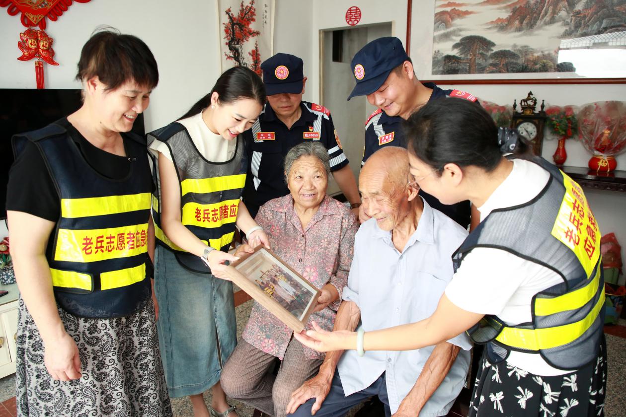 图2为：7月22日，老兵救援队员与该县海阳镇新塘村84岁老兵黄春发分享上次走访的合影照片。