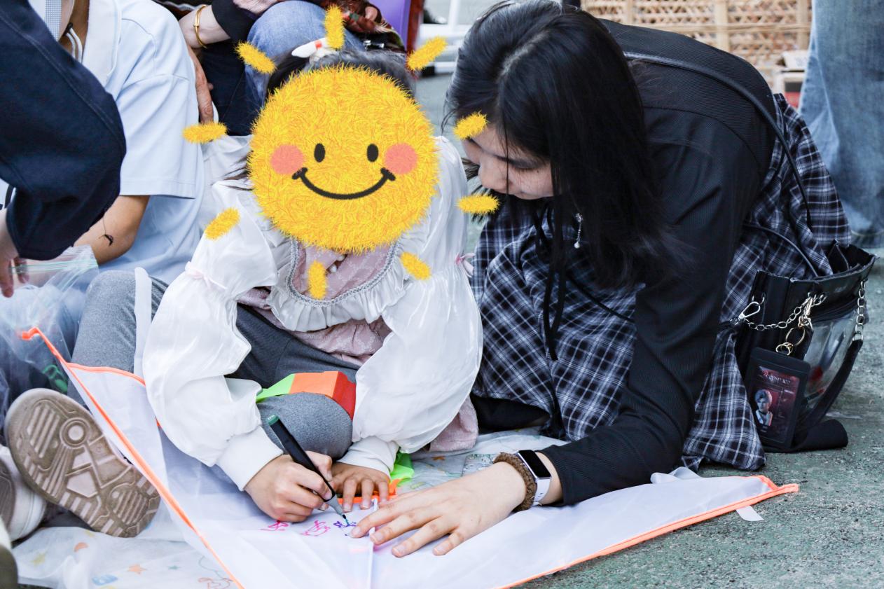 志愿者和小女孩一起绘画风筝